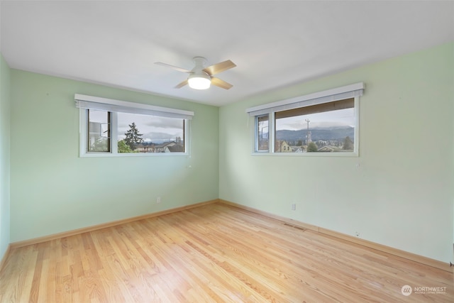 spare room featuring ceiling fan, light hardwood / wood-style flooring, and a healthy amount of sunlight