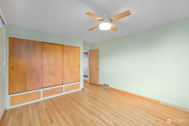 unfurnished bedroom featuring ceiling fan, light wood-type flooring, and a closet