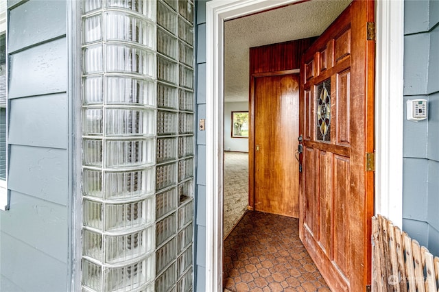 hall with a textured ceiling and wooden walls