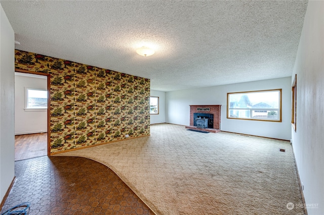 unfurnished living room featuring a textured ceiling, plenty of natural light, and a fireplace