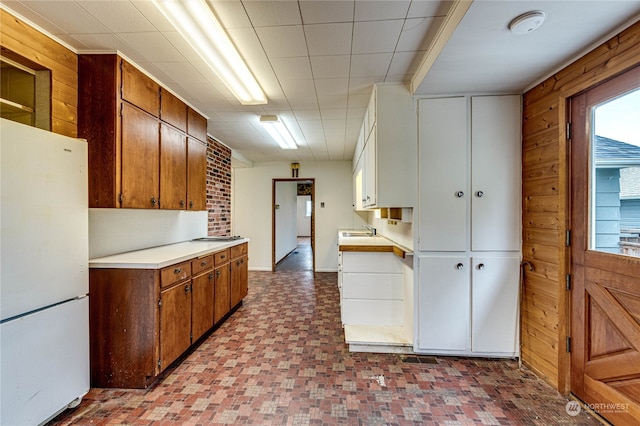 kitchen with wood walls, white fridge, and sink