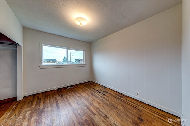 unfurnished bedroom with a closet, hardwood / wood-style floors, and a textured ceiling