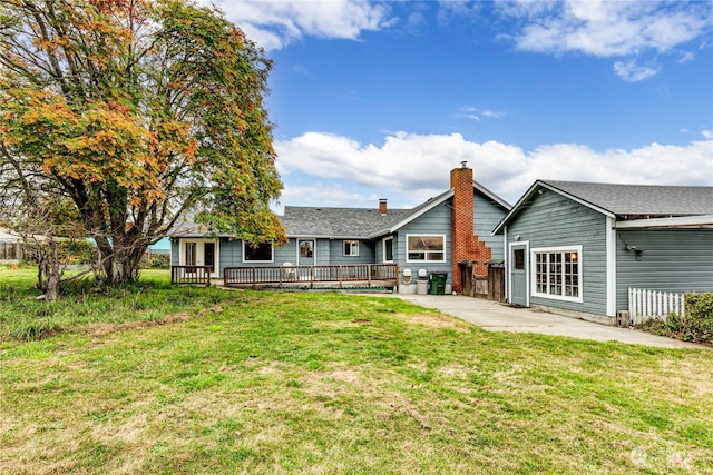 rear view of house featuring a deck and a lawn