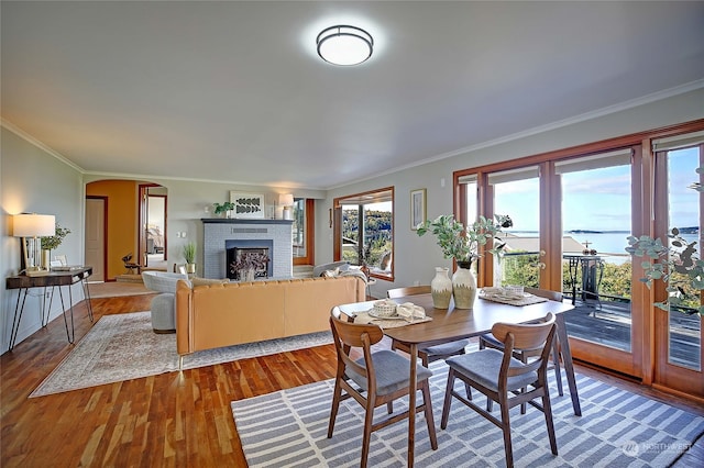 dining space featuring ornamental molding, a brick fireplace, and hardwood / wood-style floors