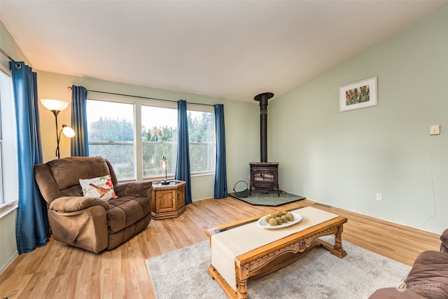 living room featuring lofted ceiling, light wood-type flooring, and a wood stove