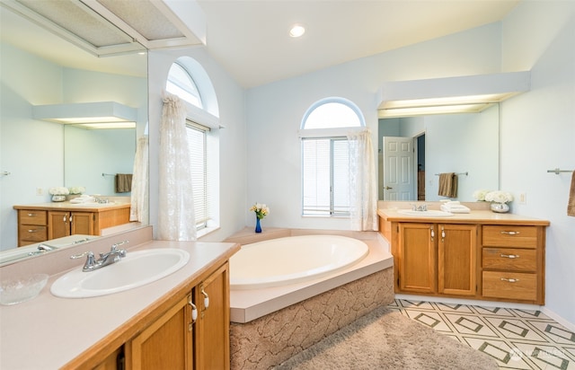 bathroom with vanity, a relaxing tiled tub, lofted ceiling, and tile patterned floors