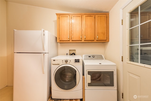 laundry area with washer and clothes dryer, a textured ceiling, and cabinets