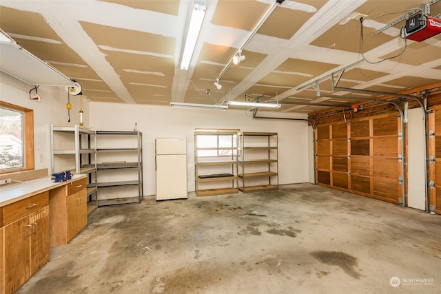 garage with a garage door opener and white refrigerator