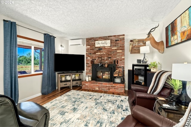 living room featuring a textured ceiling, a brick fireplace, a wall unit AC, and hardwood / wood-style floors