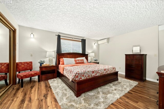 bedroom featuring a wall unit AC, a textured ceiling, and dark hardwood / wood-style flooring