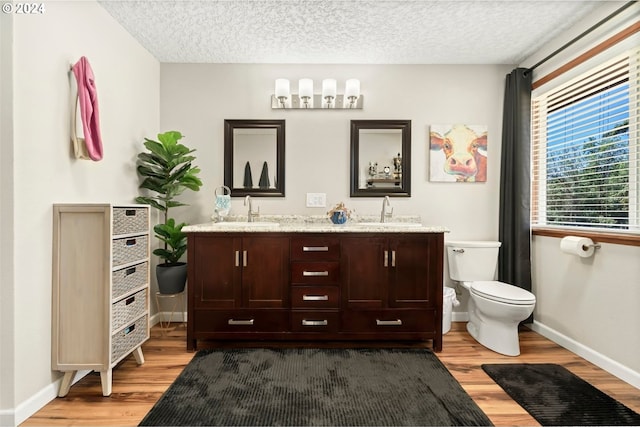 bathroom with toilet, a textured ceiling, vanity, and wood-type flooring