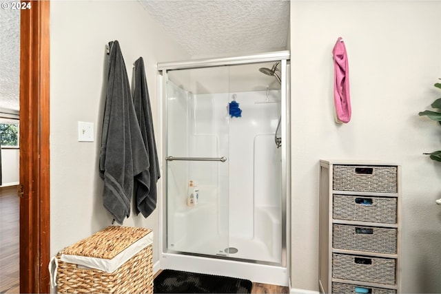 bathroom with a textured ceiling, wood-type flooring, and a shower with shower door