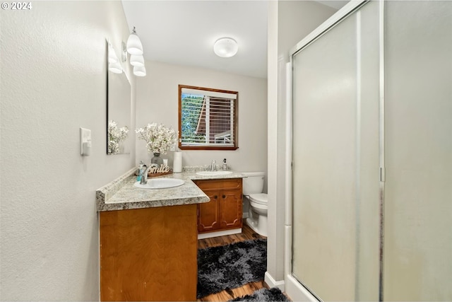 bathroom featuring vanity, toilet, hardwood / wood-style flooring, and walk in shower