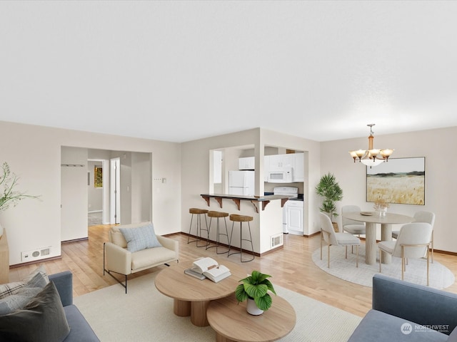 living room featuring light hardwood / wood-style flooring and an inviting chandelier