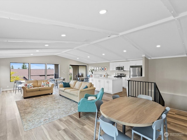 living room with lofted ceiling with beams, sink, and light wood-type flooring