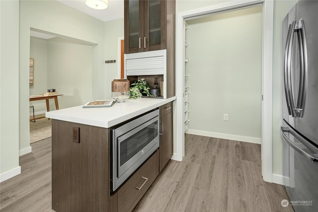 kitchen featuring appliances with stainless steel finishes, dark brown cabinetry, and light hardwood / wood-style floors