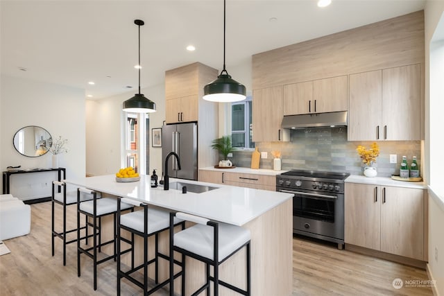 kitchen with appliances with stainless steel finishes, decorative light fixtures, light hardwood / wood-style floors, and light brown cabinets