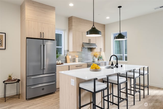 kitchen with pendant lighting, light hardwood / wood-style floors, high end appliances, and light brown cabinets