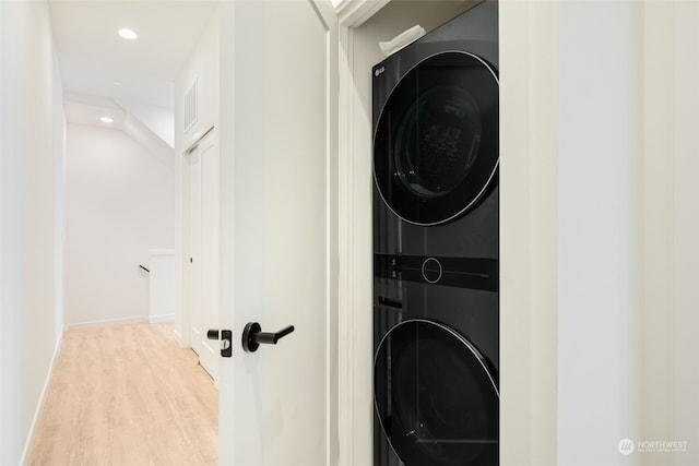 clothes washing area featuring stacked washer and dryer and light hardwood / wood-style floors