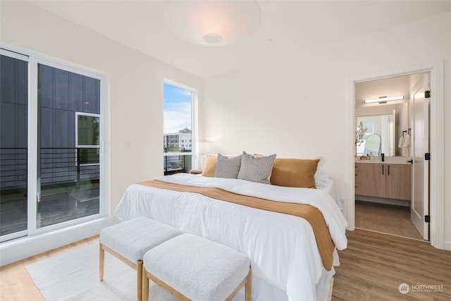 bedroom with ensuite bath and hardwood / wood-style floors