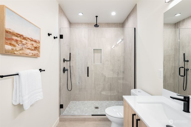 bathroom featuring vanity, a shower with shower door, and toilet