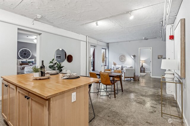 744 Market St Unit 202, Tacoma, WA 98402 - kitchen with wood counters, rail lighting, a kitchen island, finished concrete floors, and baseboards