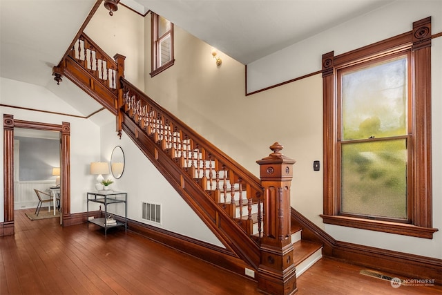 stairway with vaulted ceiling and hardwood / wood-style flooring