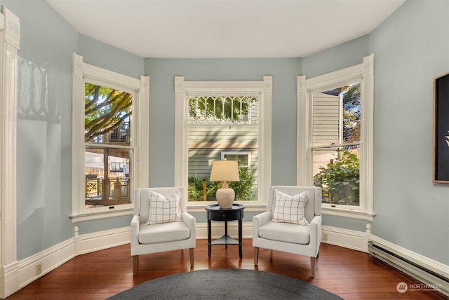 living area with a healthy amount of sunlight, dark wood-type flooring, and baseboard heating