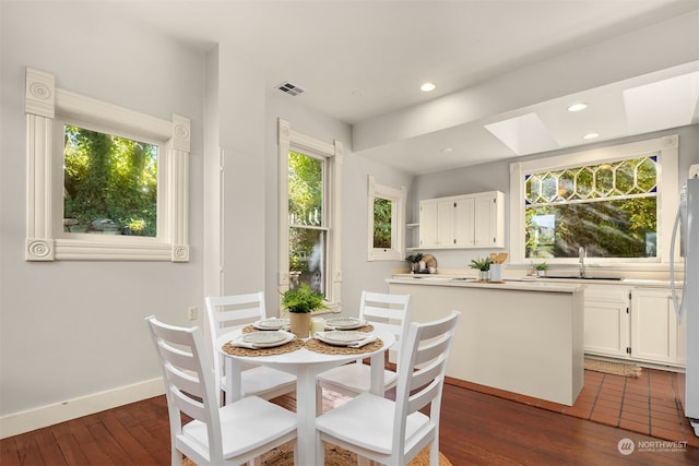 dining room featuring sink, dark wood-type flooring, and a skylight