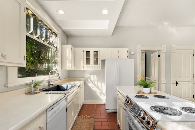 kitchen featuring dark tile patterned flooring, sink, white cabinets, white appliances, and a skylight