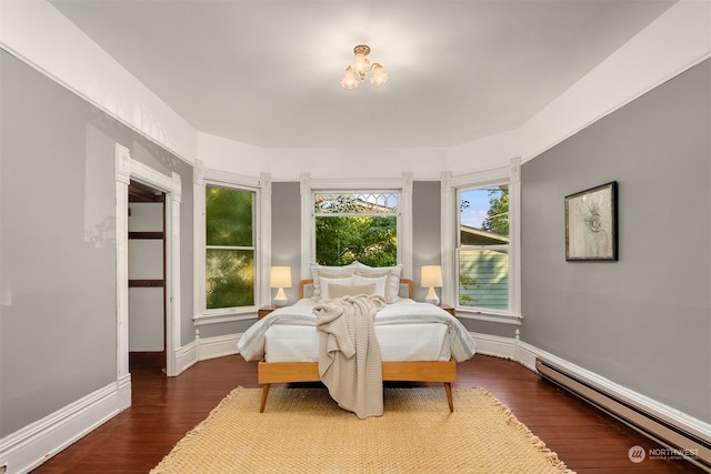 bedroom with a baseboard heating unit and dark hardwood / wood-style floors