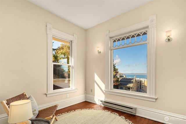 unfurnished room with dark wood-type flooring, a baseboard heating unit, and a water view