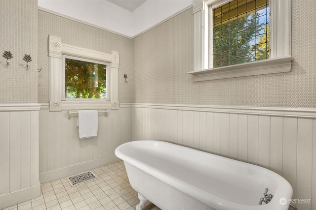 bathroom with a wealth of natural light, tile patterned floors, wooden walls, and a bathing tub