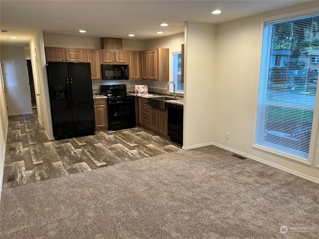 kitchen with a healthy amount of sunlight, black appliances, sink, and dark carpet