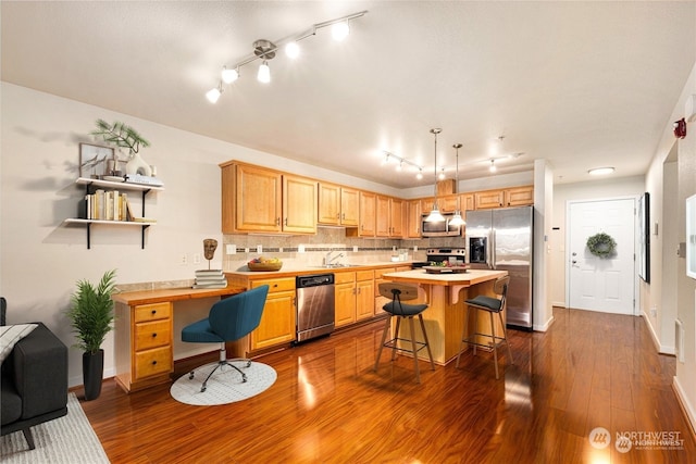 kitchen featuring decorative backsplash, dark wood-type flooring, stainless steel appliances, a breakfast bar, and a center island