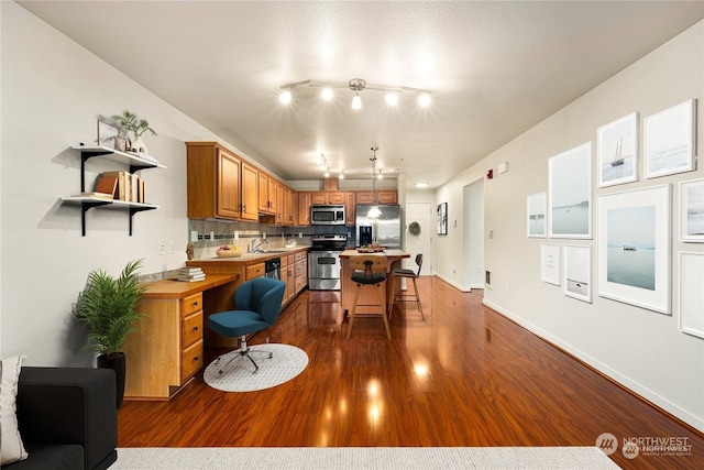 kitchen featuring appliances with stainless steel finishes, sink, a kitchen bar, a kitchen island, and backsplash