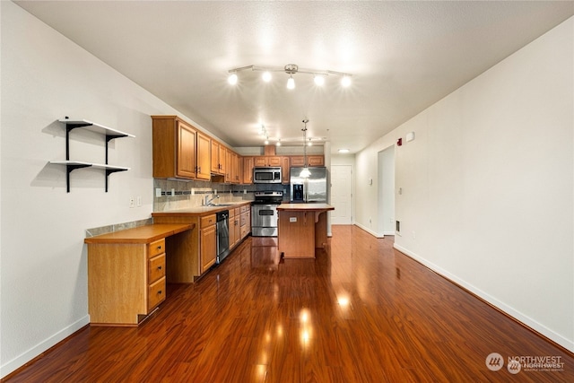 kitchen with tasteful backsplash, dark hardwood / wood-style flooring, a kitchen island, sink, and stainless steel appliances