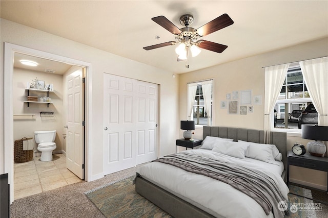 carpeted bedroom featuring a closet, ceiling fan, multiple windows, and ensuite bath