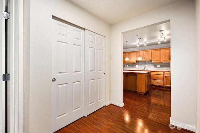 kitchen featuring dark wood-type flooring, decorative backsplash, and decorative light fixtures