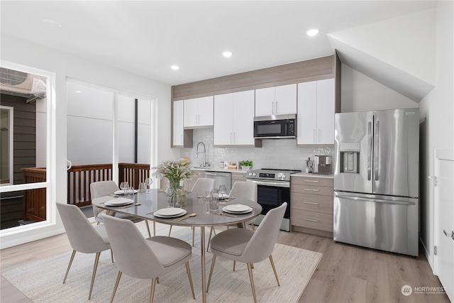 kitchen featuring stainless steel appliances, white cabinetry, tasteful backsplash, and light hardwood / wood-style floors