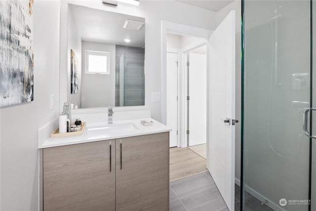 bathroom featuring vanity, a shower with shower door, and wood-type flooring