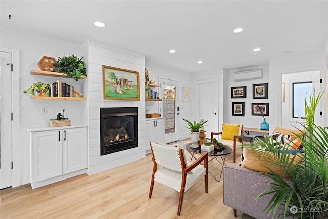 living room featuring a wall mounted AC and light hardwood / wood-style flooring