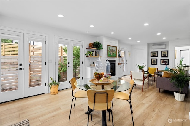 dining space with french doors, a wall mounted air conditioner, and light wood-type flooring