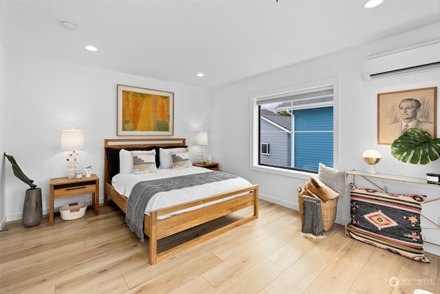 bedroom with a wall mounted AC and light wood-type flooring