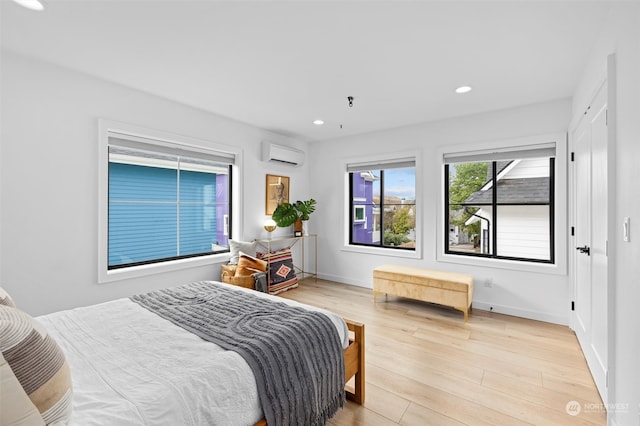 bedroom with a wall mounted AC and light hardwood / wood-style flooring