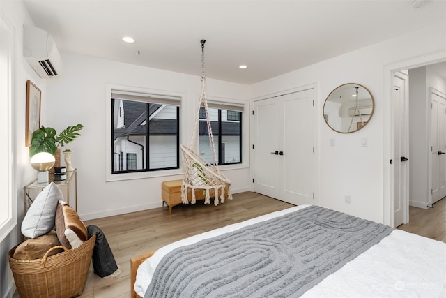 bedroom featuring light hardwood / wood-style floors, a closet, and an AC wall unit