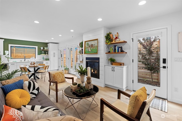 living room with a fireplace, sink, and light wood-type flooring