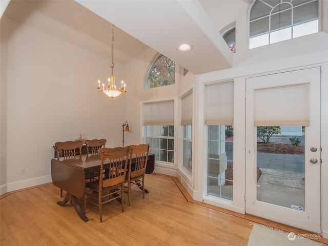 dining area featuring light hardwood / wood-style flooring, a notable chandelier, and high vaulted ceiling