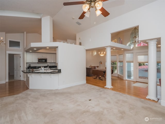 unfurnished living room featuring light hardwood / wood-style flooring, ornate columns, and high vaulted ceiling