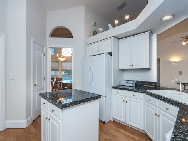 kitchen with ceiling fan, a kitchen island, white cabinetry, light wood-type flooring, and white fridge